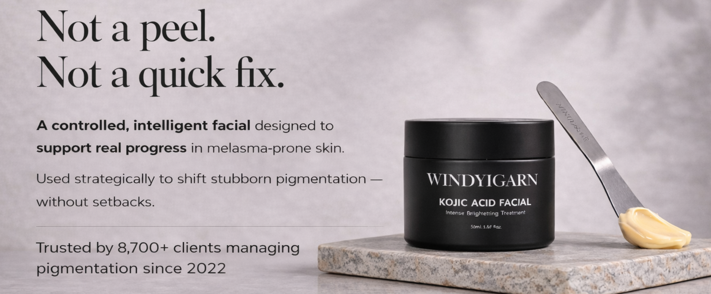 Black jar of Windyigarn Kojic Acid Facial on a marble slab with text about the product.